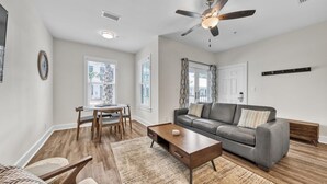 A modern living room with a gray sofa, wooden coffee table, and a ceiling fan. - Hidden Lake Condos 113 (Santa Rosa Beach)