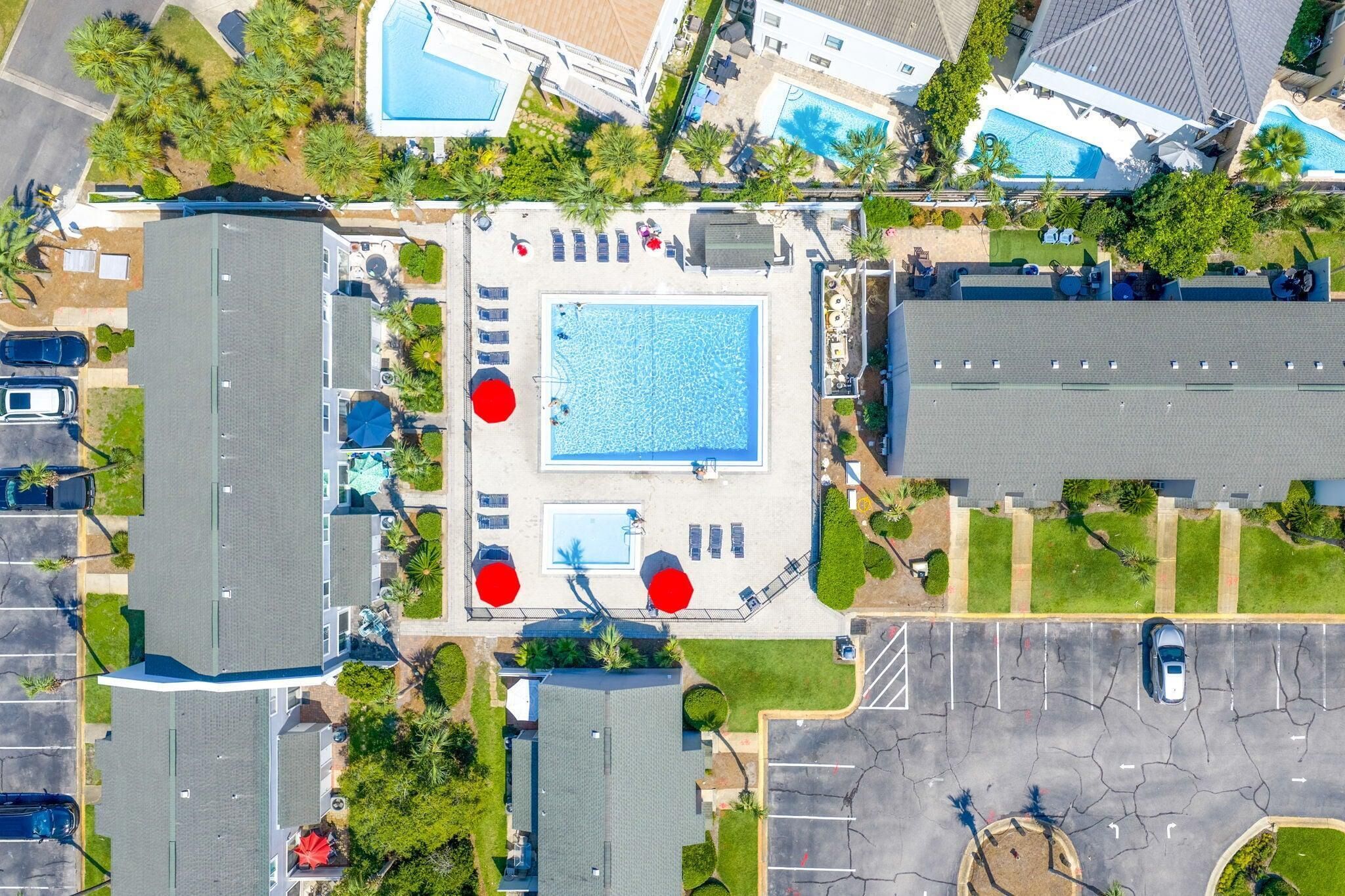 Vue aérienne d’un complexe hôtelier doté de plusieurs piscines, de chaises longues et d’un parking.