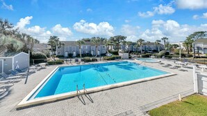 A rectangular swimming pool with a tiled deck, surrounded by lounge chairs and a small deck area.