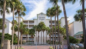A hotel named Crystal Dunes with a white facade, multiple balconies, and palm trees in the foreground. - Crystal Dunes 405 (Destin)
