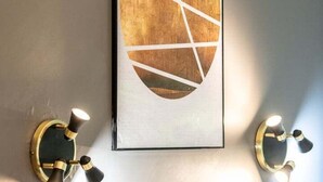 A framed abstract artwork on a wall, flanked by two wall-mounted light fixtures. - Central Part-Dieu - Apartment 2 - A/C available (Lyon)