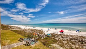 A beach with a sandy path leading to the water, a wooden deck, and beach umbrellas. - Crystal Villas 6A (Destin)