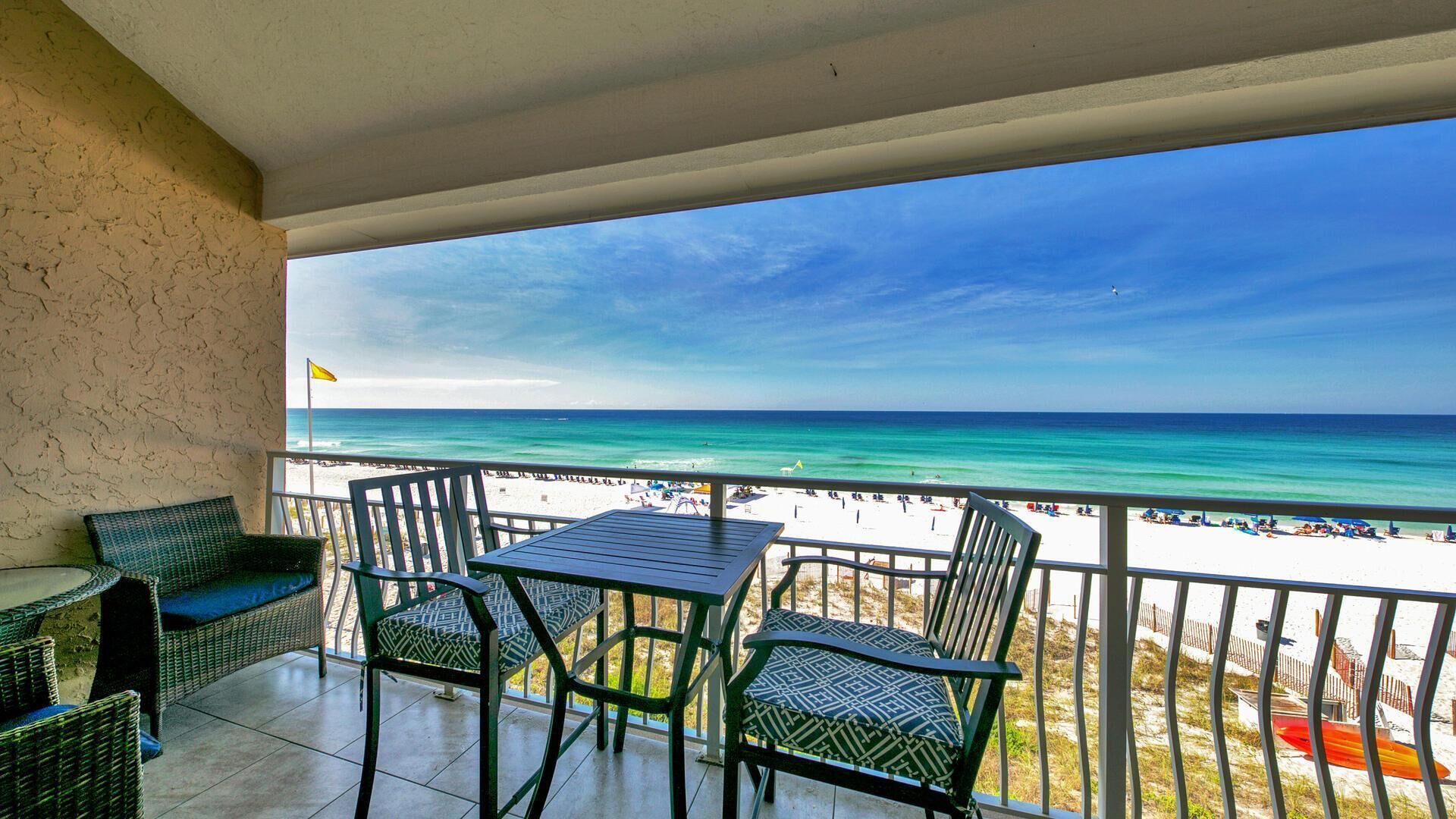 A balcony with a view of the beach and ocean.