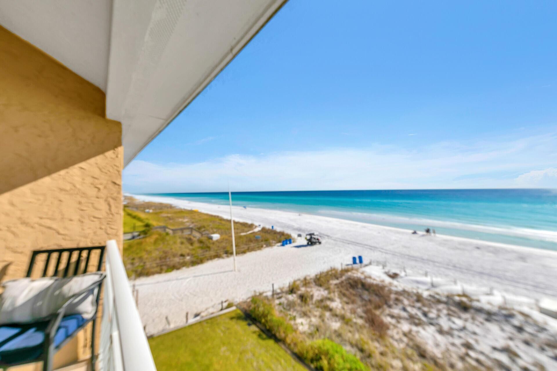 A beach view from a balcony with a clear sky.