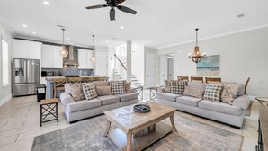 A modern living room with a sofa set, coffee table, and a ceiling fan. - Wanderlust (Destin)
