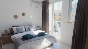 A bedroom with a bed, nightstands, and a view of a balcony. - Stunning 2 Bedroom, 2 Bathroom apt St Julians (St. Julian's)