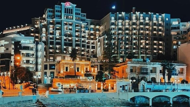 A coastal hotel with multiple balconies, a bridge, and a beach in the foreground. - Stunning 2 Bedroom, 2 Bathroom apt St Julians (St. Julian's)