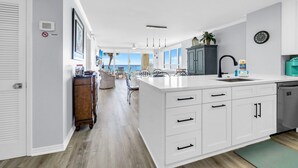 A modern kitchen with white cabinetry, a central island, and a view to the outside. - Hidden Dunes Gulfside 206 (Miramar Beach)