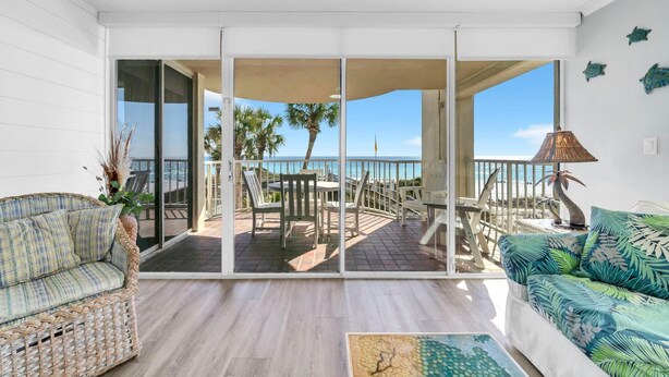 A balcony with a view of the sea, wicker furniture, and a tropical-themed sofa. - Hidden Dunes Gulfside 206 (Miramar Beach)