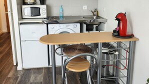 A compact kitchen with white cabinets, a microwave, a washing machine, and a red kettle. - Paris15/parc des Expositions/Issy-les-Moulineaux  (Issy-les-Moulineaux)