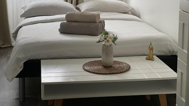 A neatly made bed with towels, a vase with flowers, and a bedside table in a modern room with a window and curtains. - Paris15/parc des Expositions/Issy-les-Moulineaux  (Issy-les-Moulineaux)