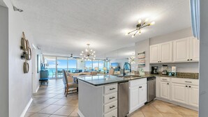 A spacious kitchen with a large island, white cabinetry, and a view to the outside. - Hidden Dunes Gulfside 502 (Miramar Beach)
