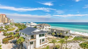 A coastal residential area with modern houses, a beach, and a clear view of the ocean. - Hidden Dunes Gulfside 502 (Miramar Beach)
