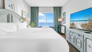 A hotel room with a large bed, a television, and a view of the ocean. - Leeward Key 1103 (Miramar Beach)