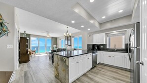 Una cocina amplia con una isla grande, armarios blancos y vistas al exterior.