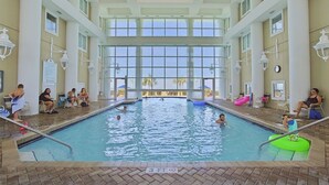 Una piscina interior con paredes de vidrio transparente, varios niveles de asientos y suelo de baldosas.