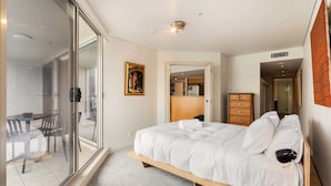 Una camera da letto con un letto, una cassettiera in legno, una scrivania e un'area pranzo con sedie.