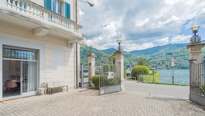 A building with a balcony, a gate, and a view of a lake and mountains. - Piccola Como Lotus With 1 Bathrooms (Carate Urio)