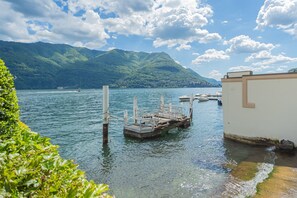 Een meer met boten, een steiger en bergen op de achtergrond.