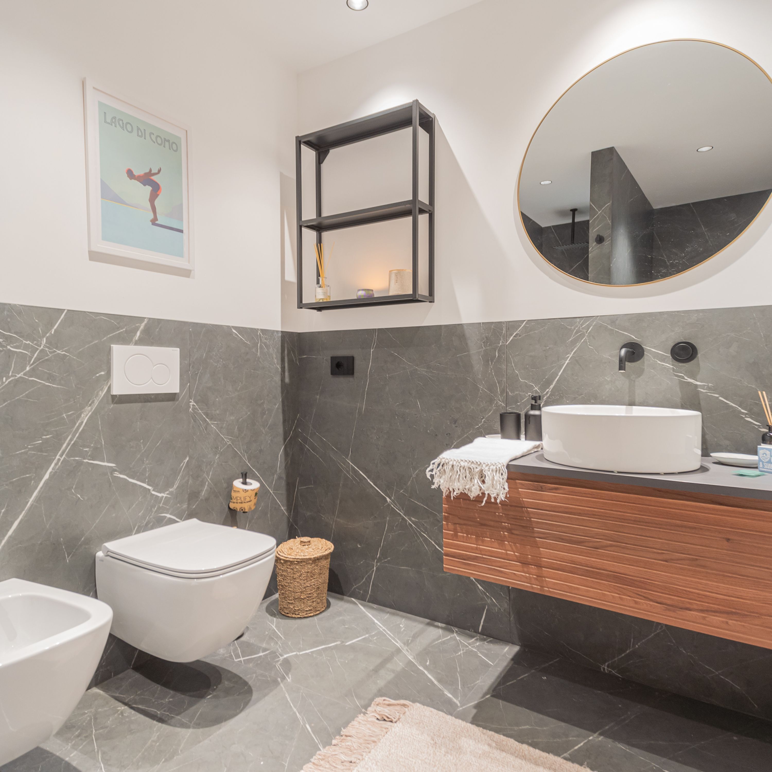 A modern bathroom with a toilet, bidet, vanity with a sink, and a mirror.