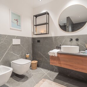 Un bagno moderno con toilette, bidet, mobile lavabo e specchio.