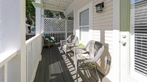 A covered porch with wicker furniture and a white door. - Aventon (Miramar Beach)