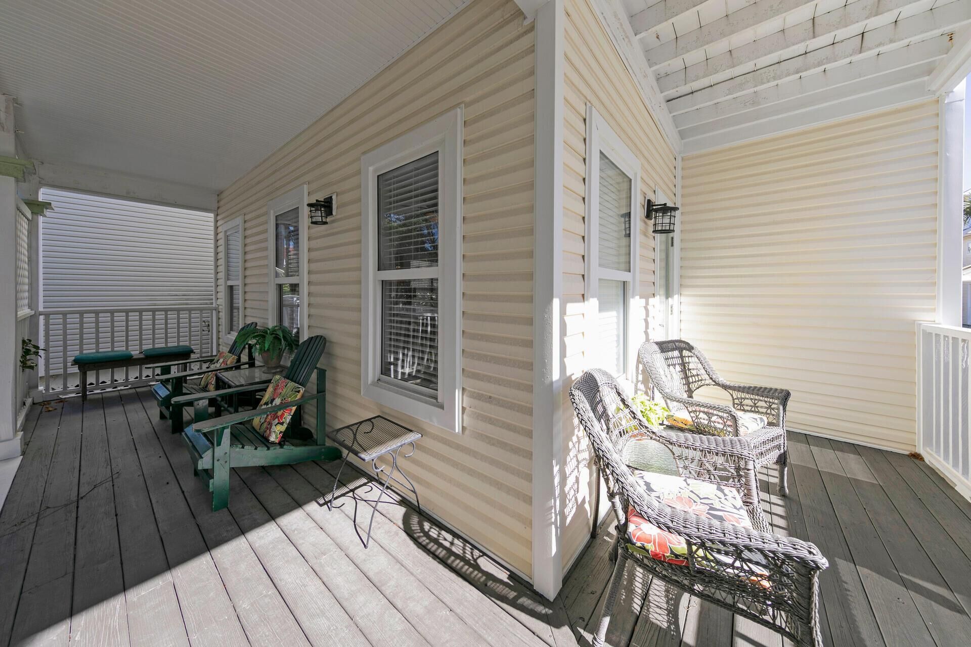 A covered porch with outdoor furniture, including chairs and a table, and a potted plant.