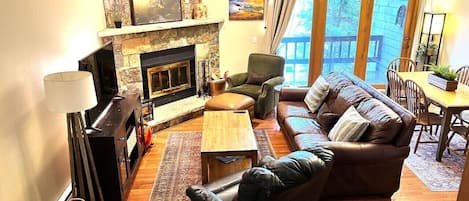 Una sala de estar acogedora con chimenea, sofá de cuero y comedor.