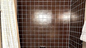 A bathroom with a bathtub, a shower, and a tiled wall.