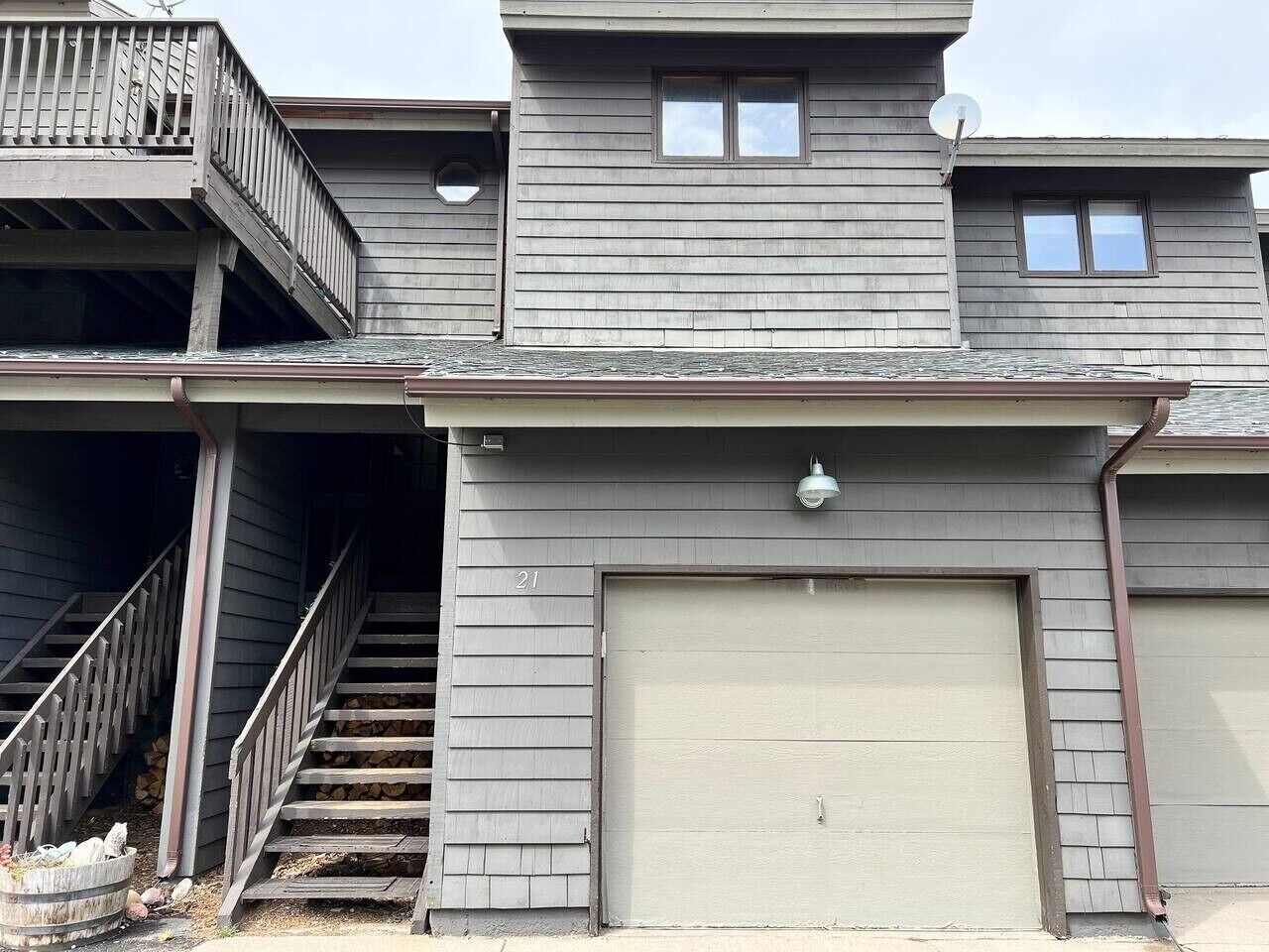 A two-story building with a garage door, a balcony, and a staircase leading to the upper floor.