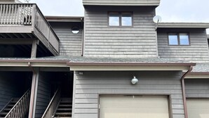 A two-story building with a garage door, a balcony, and a staircase leading to the upper floor.