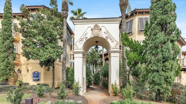 An archway with "Saint" and "Tropes" inscribed, leading to a pathway surrounded by greenery and buildings. - Monaco (Miramar Beach)