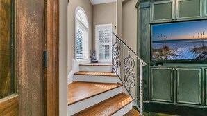A staircase with wooden steps and a metal railing, leading to a balcony with a view of the ocean. - Monaco (Miramar Beach)