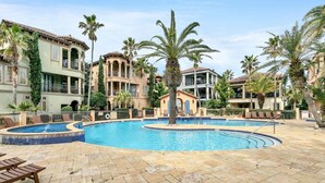 A pool area with a circular pool, lounge chairs, and palm trees. - Monaco (Miramar Beach)