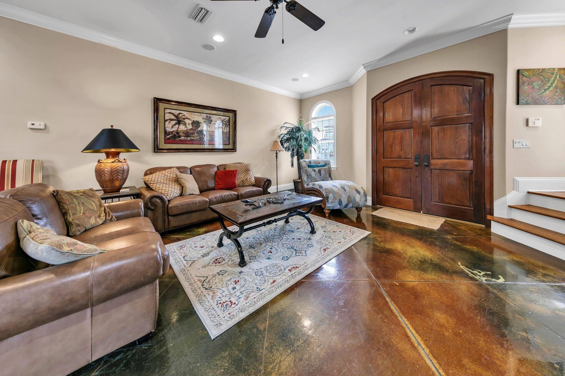 A spacious living room with a leather sofa, a coffee table, and a large wooden door.
