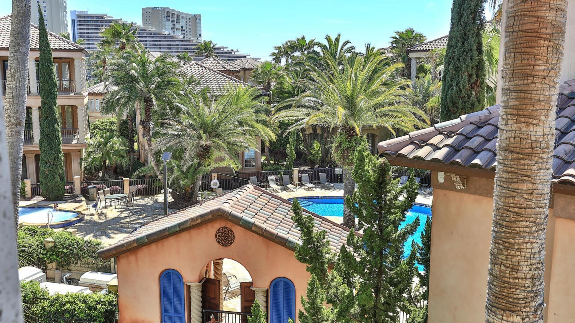 Un resort con piscina, palmeras y vistas a un horizonte urbano.