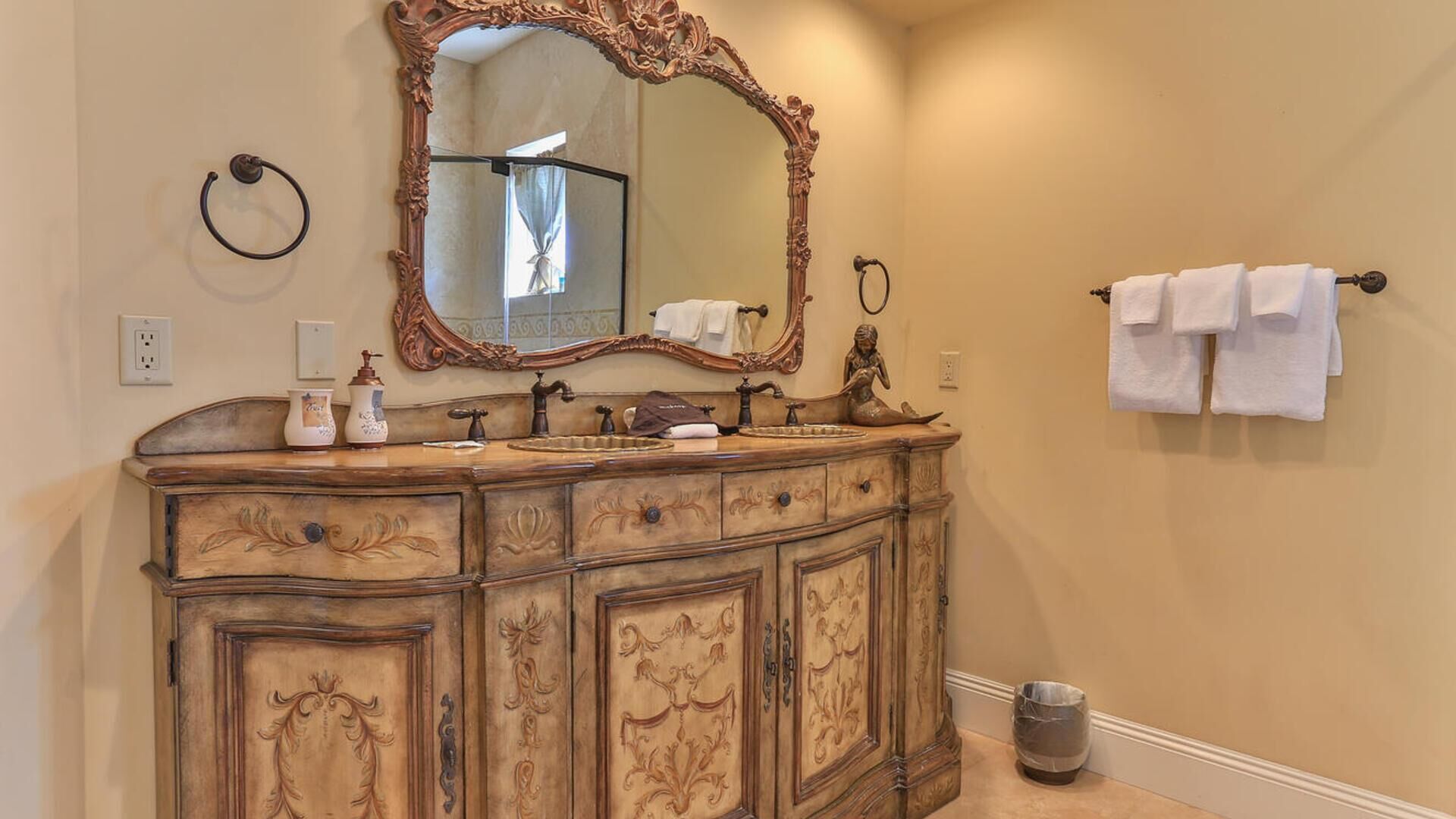 A bathroom with an ornate vanity, a large mirror, and a towel rack.