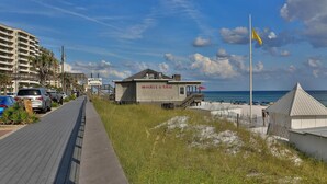 En restaurant ved stranden, der hedder 'Whale's Tail', med udsigt til havet, en træpromenade og et sandstrandområde.