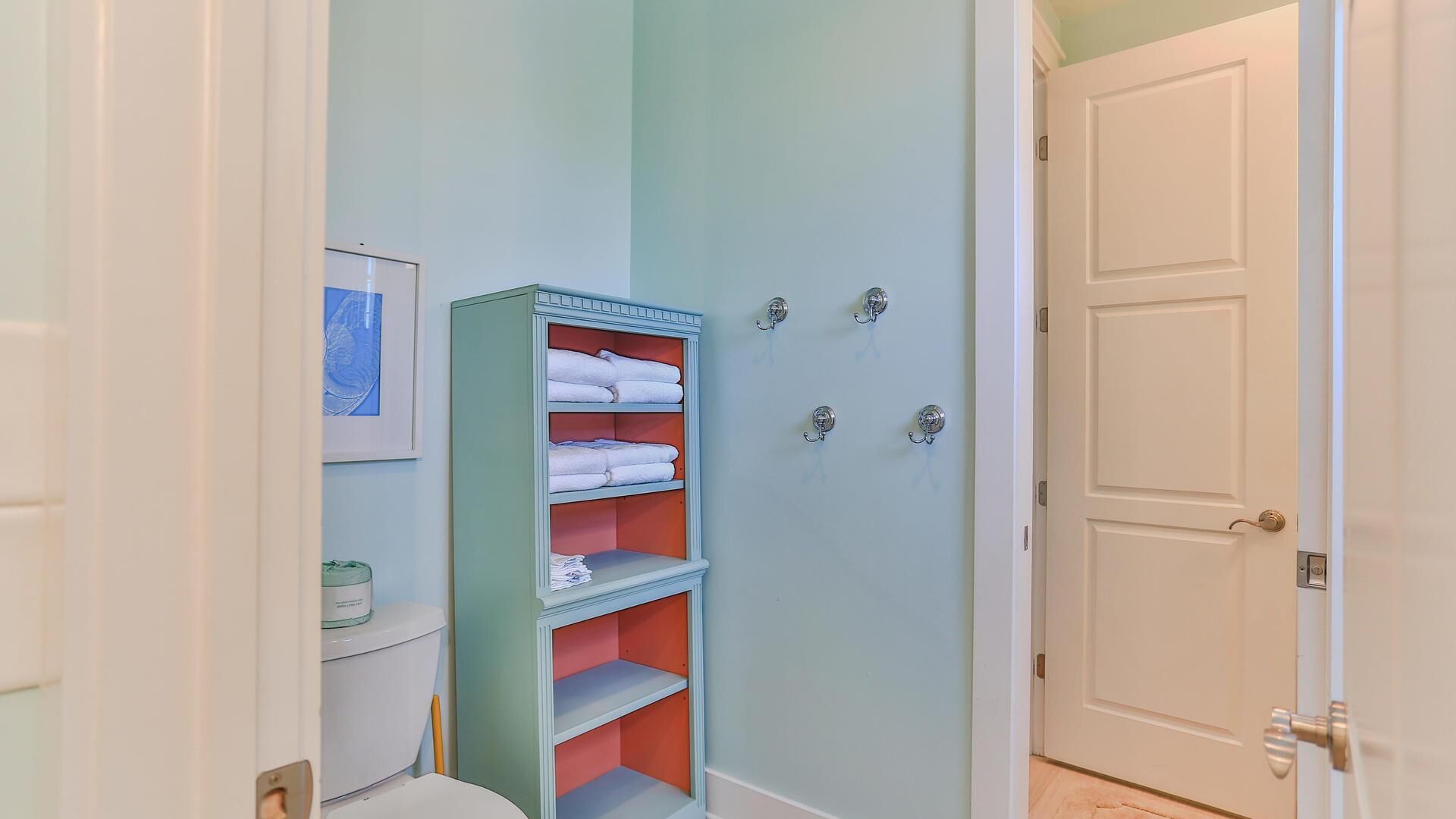 Une salle de bain équipée de toilettes, d’un porte-serviettes et d’une étagère avec des serviettes.