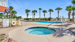 A swimming pool area with a hot tub, surrounded by palm trees and a clear sky. - Destin Towers 102 (Destin)