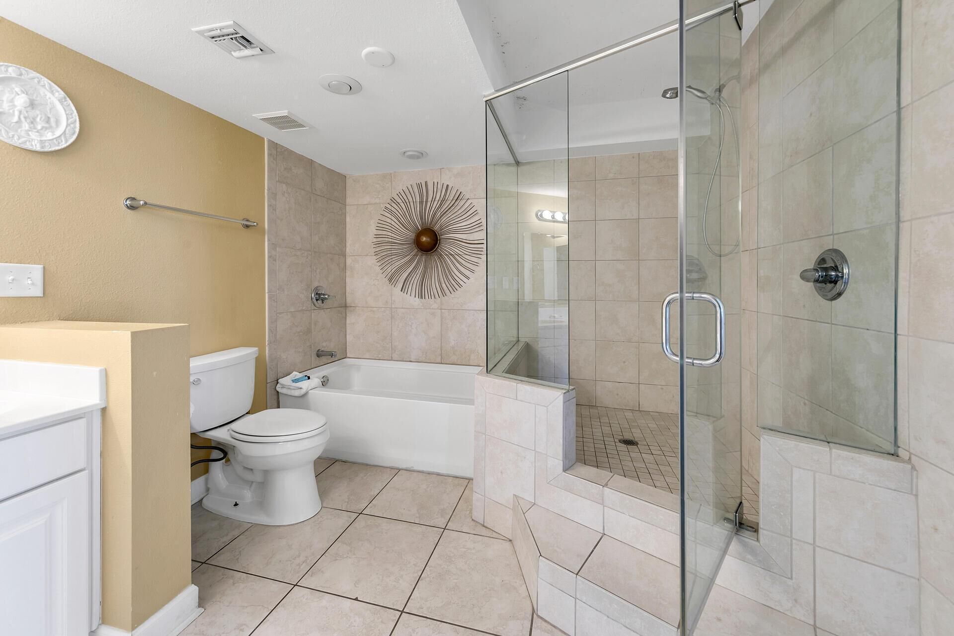A modern bathroom with a glass-enclosed shower, a white toilet, and a bathtub.
