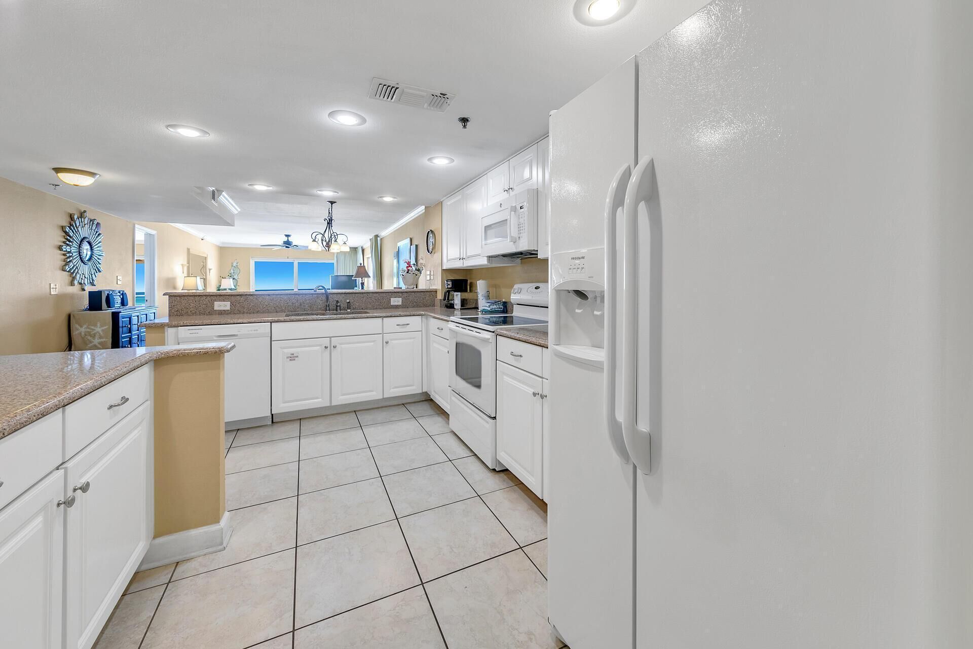 A modern kitchen with white cabinetry, a built-in oven, and a refrigerator.