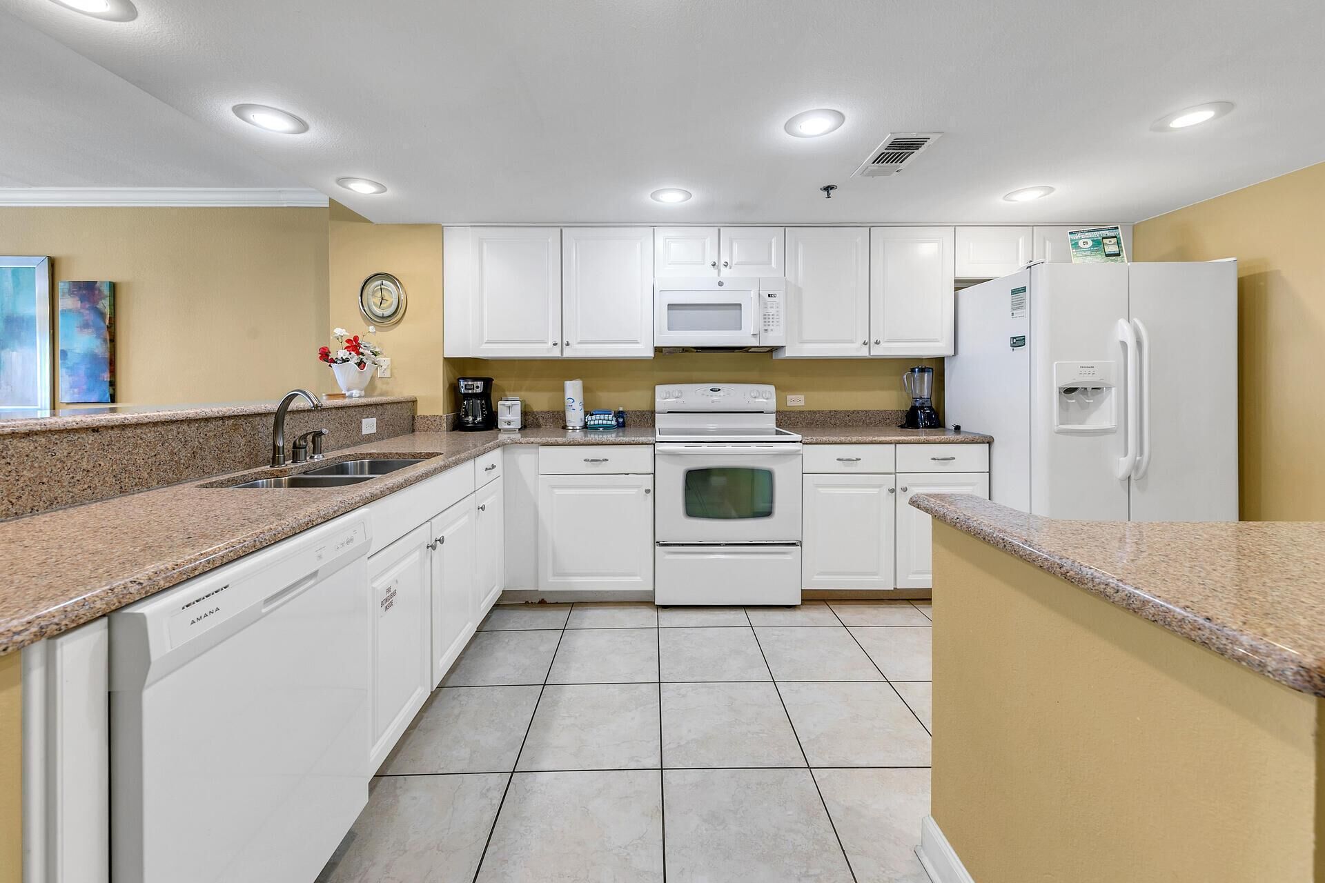 A kitchen with white cabinets, a microwave, an oven, a sink, and a refrigerator.