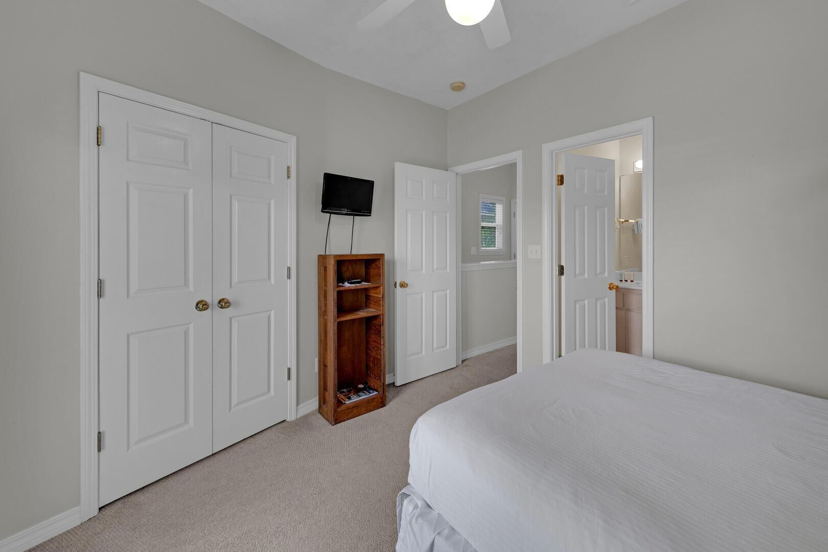 A bedroom with a bed, a wooden bookshelf, and a television mounted on the wall.