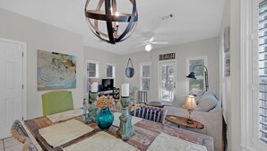 A dining area with a wooden table, green chairs, and a blue vase. There is a ceiling fan and a painting on the wall. - Pops Place (Santa Rosa Beach)