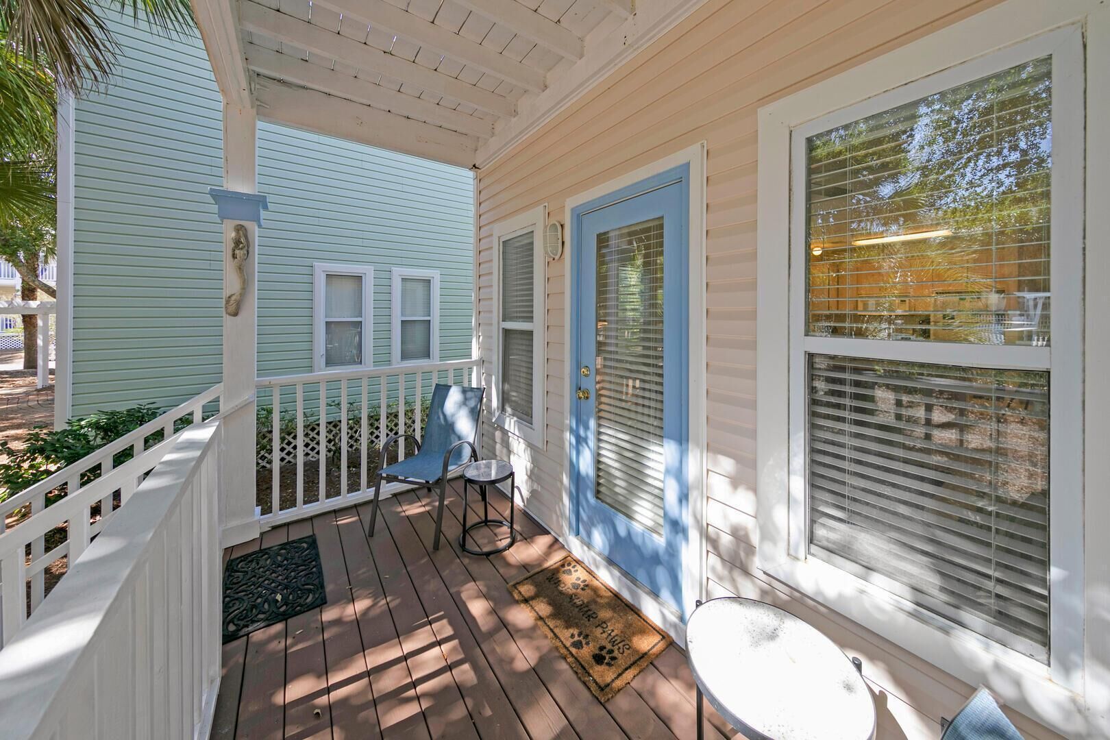 A porch with a white railing, a blue door, and a small table.