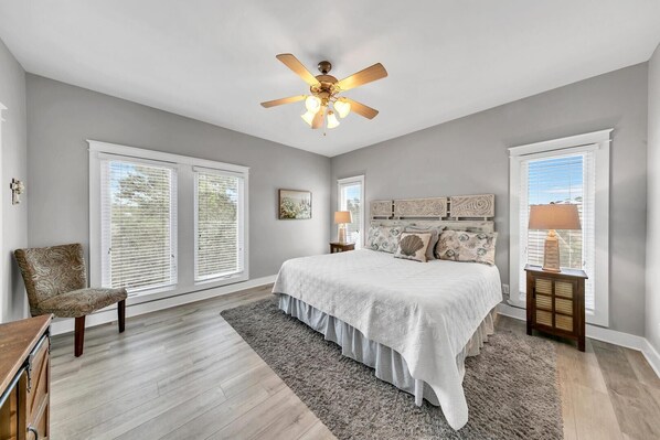 A bedroom with a bed, a chair, a nightstand, a lamp, and a ceiling fan. - Seashine and Sunkisses (Santa Rosa Beach)