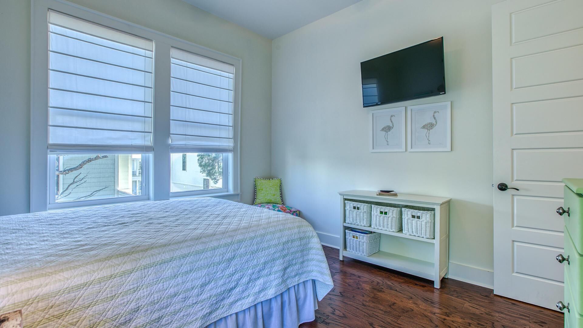 A bedroom with a bed, a television, and a white wardrobe.