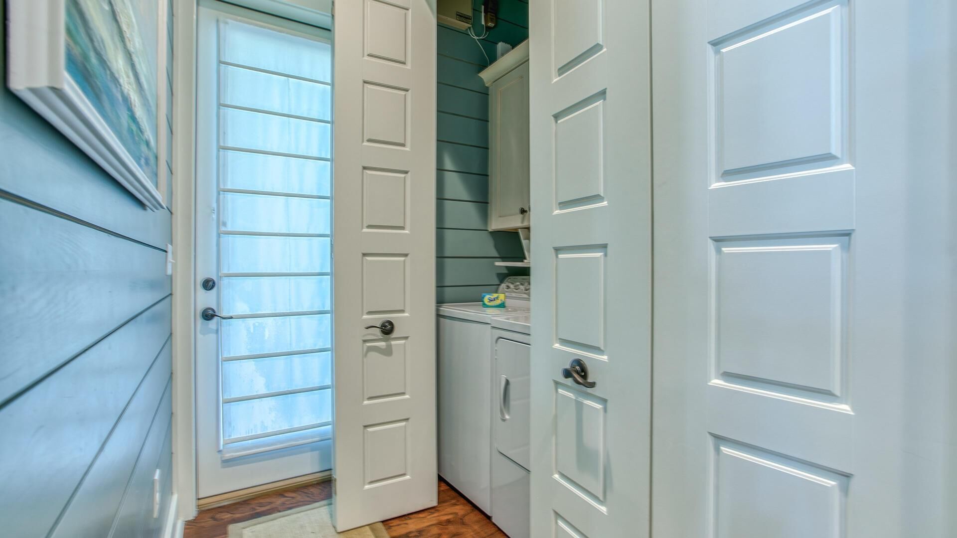 A narrow hallway with a door leading to a laundry area.