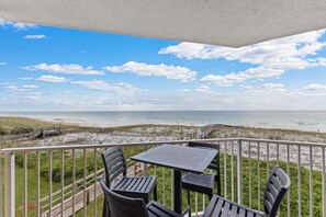 A balcony with a table and chairs overlooking a beach. - Destin on the Gulf 307 (Destin)